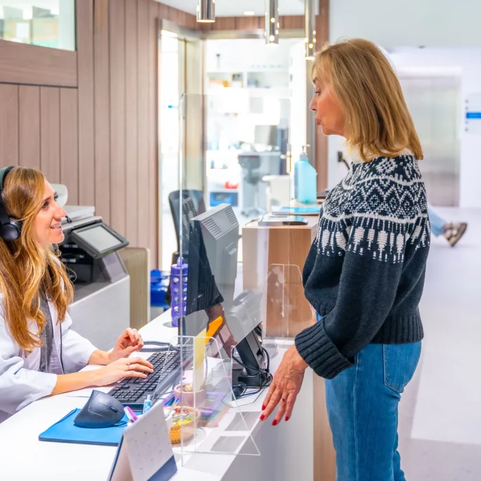A receptionist assisting a patient at the entrance of Eastgardens Medical Centre